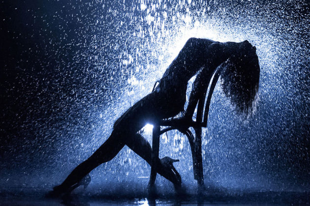 Flashdance's famous pose: a dancer leans back on a chair as water splashes down on her