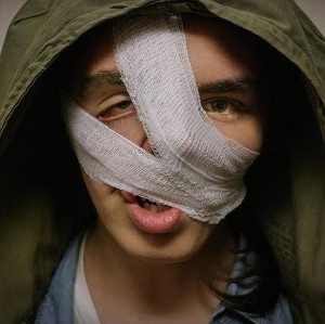Still from Happy Face: Stan, his face wrapped in bandages under a green hood