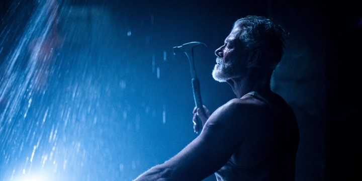 Still from Don't Breathe 2: the Blind Man raises a hammer in a beam of blue light