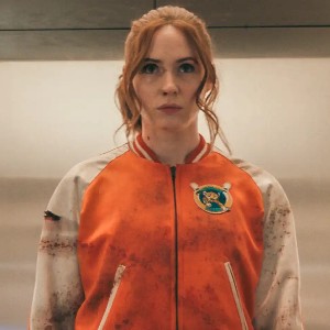 Still from Gunpowder Milkshake: a woman in a bloodied orange varsity jacket