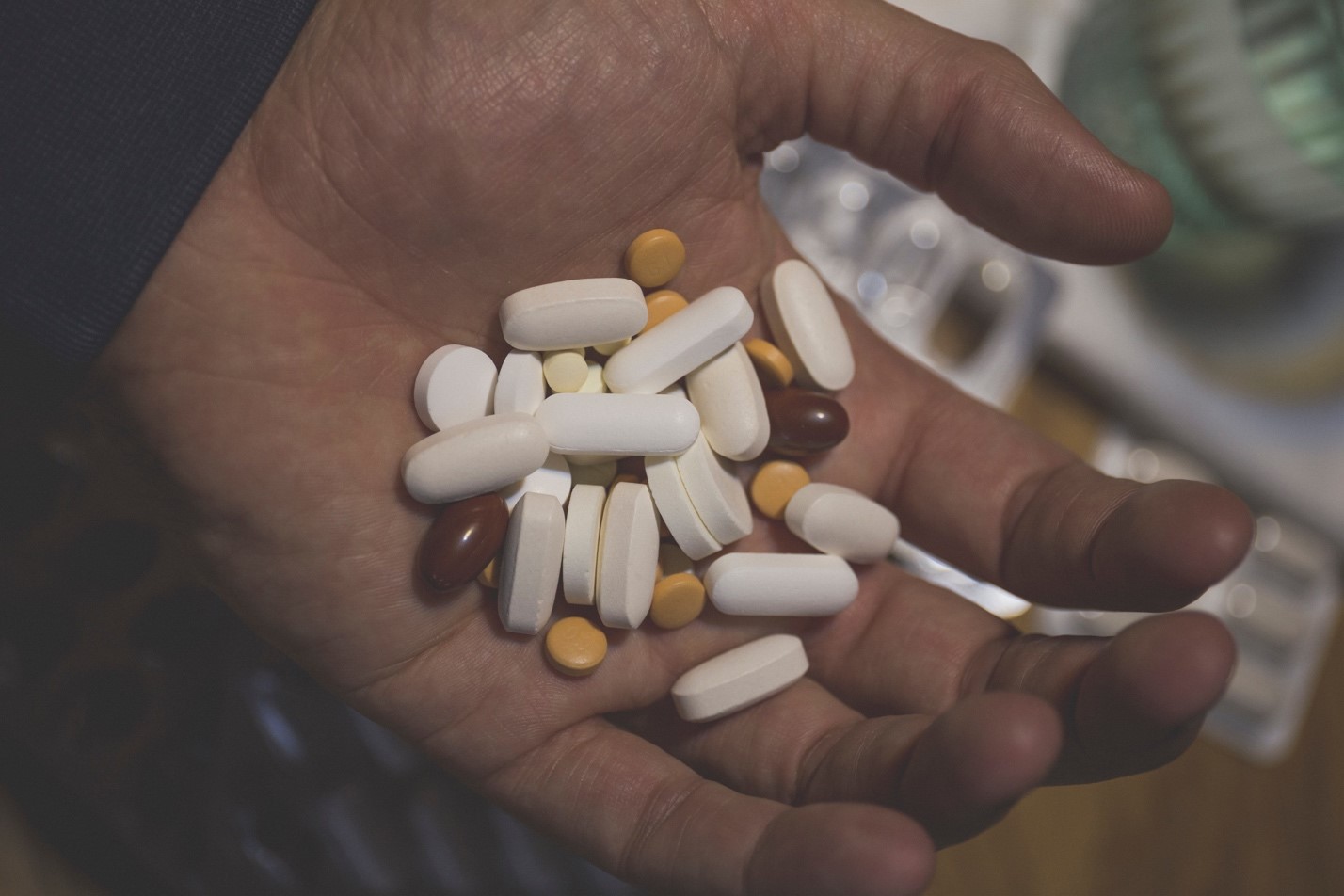 Hand holding a pile of assorted pills