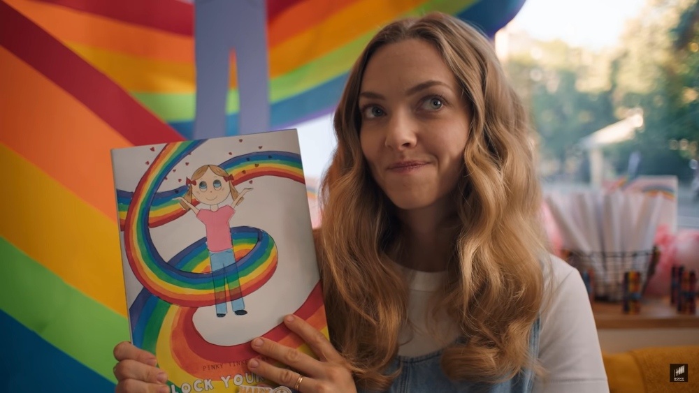 Still from A Mouthful of Air: a woman holds up a rainbow picture book