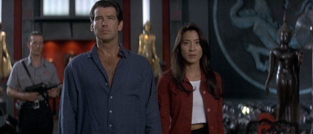 Still from Tomorrow Never Dies: James Bond and Wai Lin stand side by side, an armed guard behind them