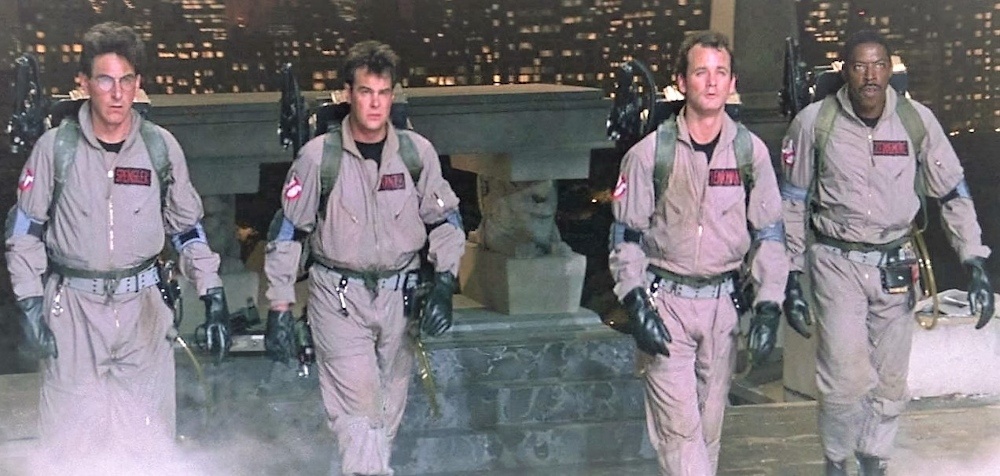 Still from Ghostbusters (1984): the four Ghostbusters walk forward in jumpsuits and proton packs