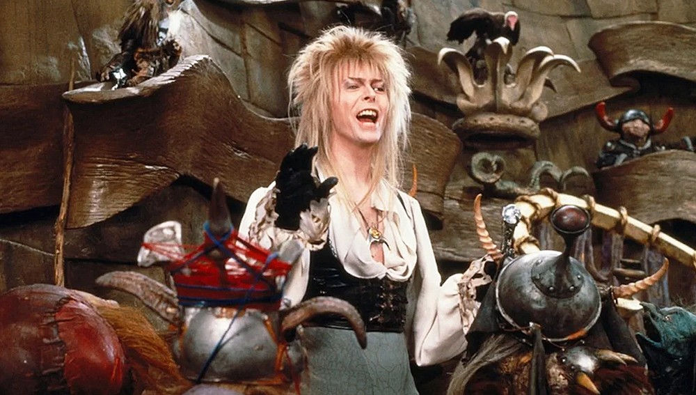 Still from Labyrinth: David Bowie as the Goblin King sings among puppet goblins