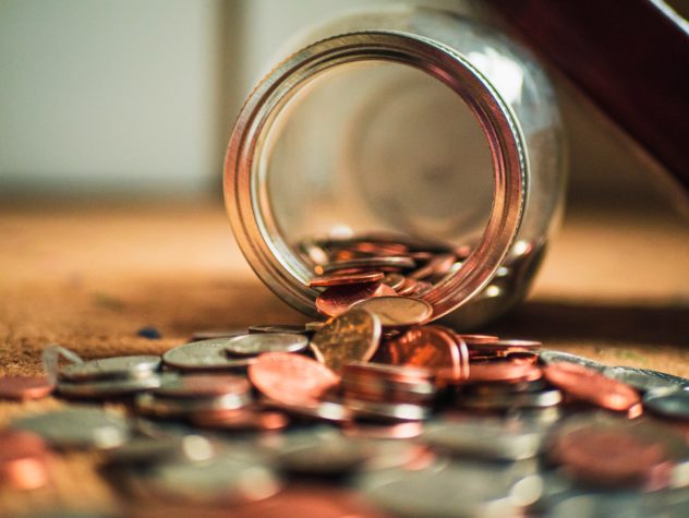 Coins spilling from an overturned glass jar