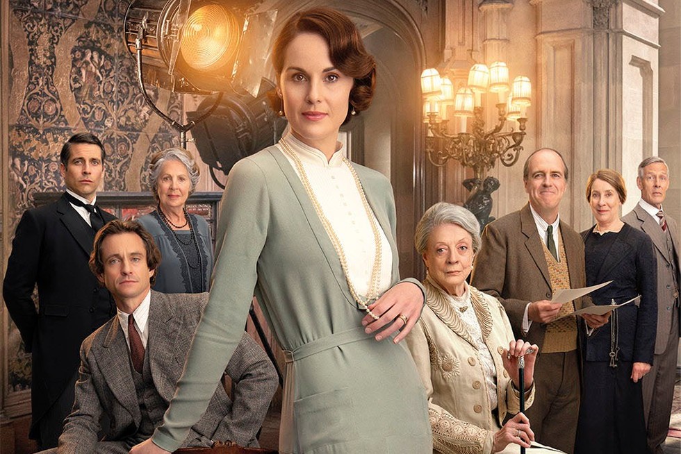 Poster art for Downton Abbey: A New Era showing the cast posed in a grand hall with a film light