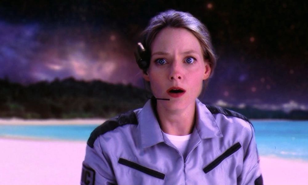 Still from Contact: Ellie, wearing a headset, stares in awe on a glowing alien beach under a starry sky