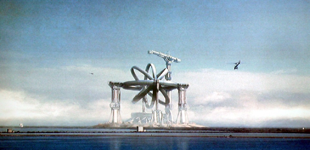 Still from Contact: the giant spinning-ring Machine stands over the water as a helicopter flies past
