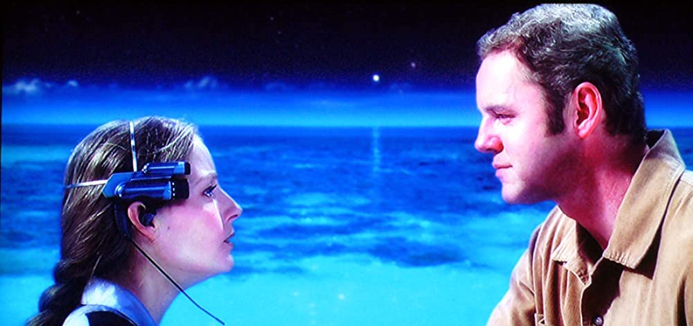 Still from Contact: Jodie Foster, wearing a headset, faces David Morse on a glowing alien beach