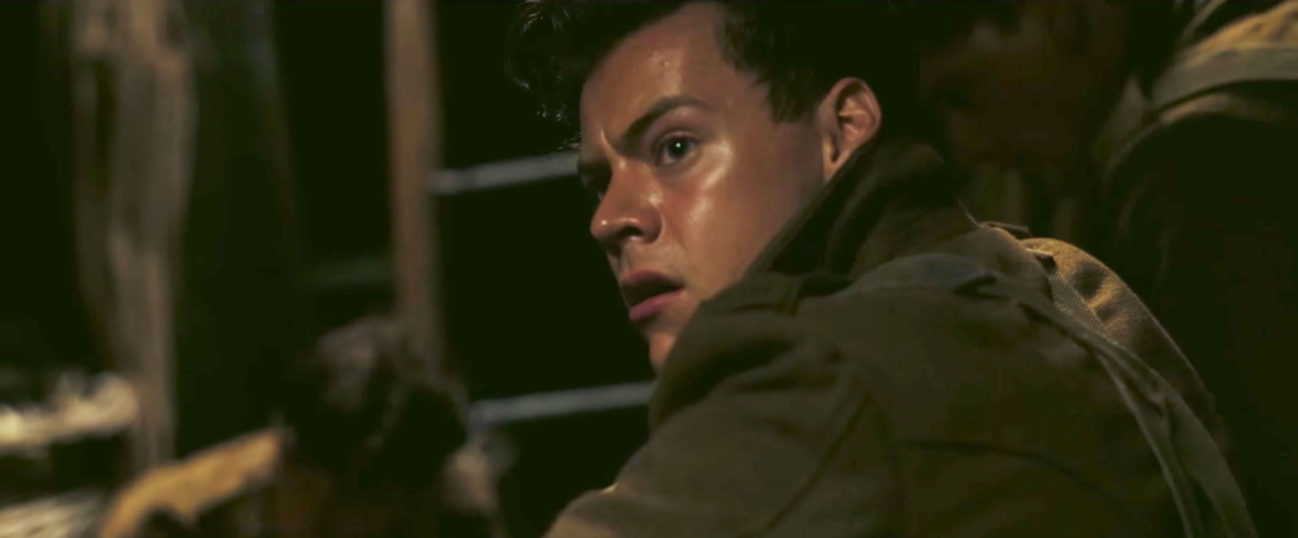 Still from Dunkirk: a young soldier in a dark ship's hold looks back in alarm