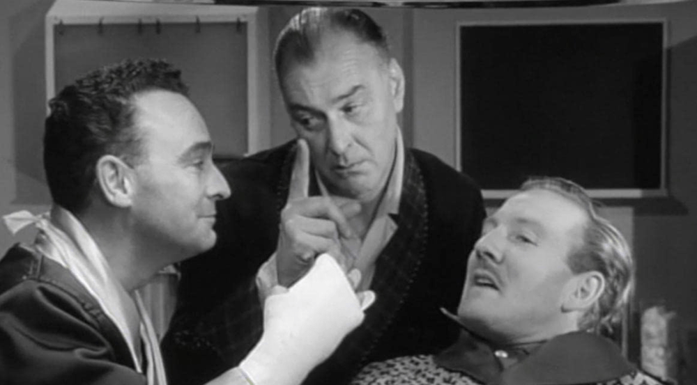 Still from Carry On Nurse (1959): two men lean over a patient in a hospital bed, one raising a finger