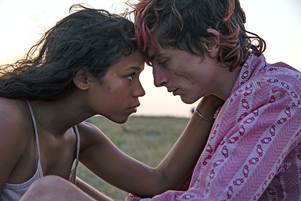 Still from Bones and All: a young couple lean forehead to forehead in an open field