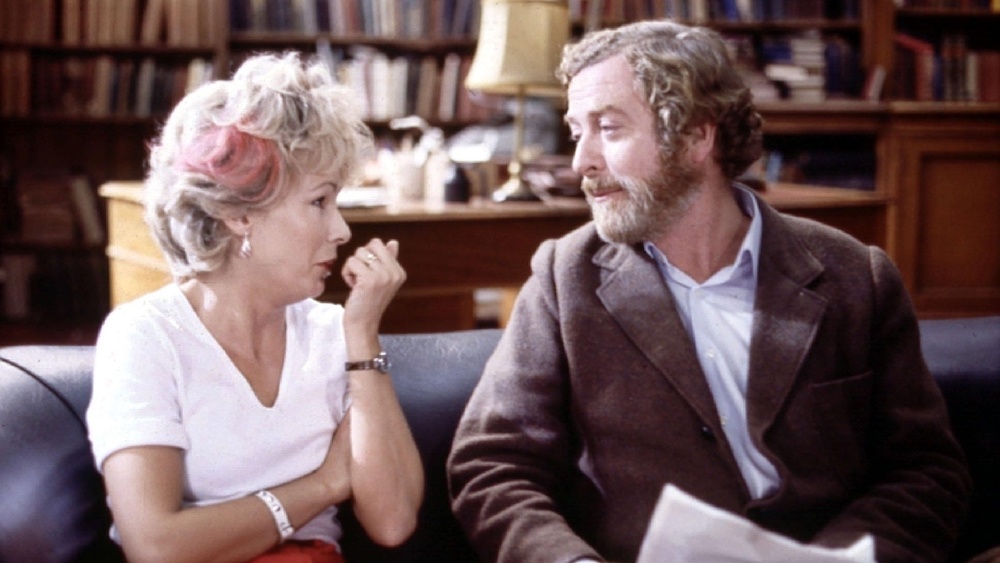 Still from Educating Rita: Julie Walters as Rita talks with Michael Caine's tutor on a sofa in a book-lined study