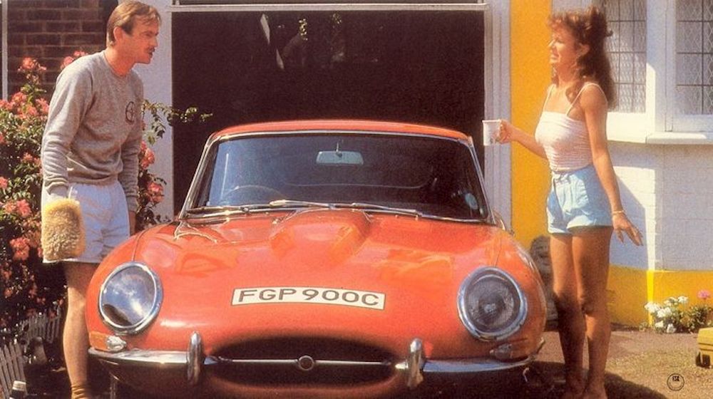 Still from Car Trouble (1986): Julie Walters and Ian Charleston with a red E-Type Jaguar