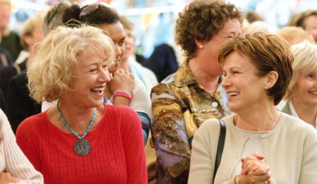 Helen Mirren and Julie Walters laughing together in a crowd in Calendar Girls
