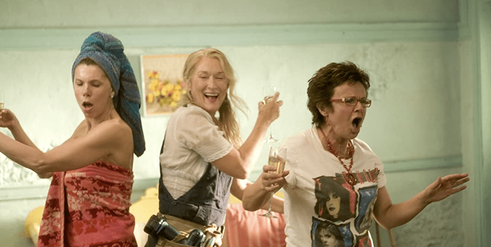 Still from Mamma Mia!: Christine Baranski, Meryl Streep and Julie Walters dance and sing with champagne glasses