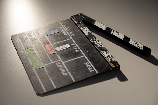 A worn film clapperboard lying open on a table