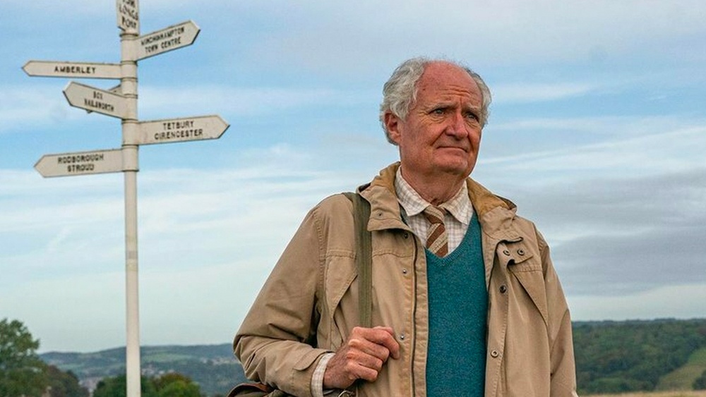 Still from The Unlikely Pilgrimage of Harold Fry: Harold stands by a country signpost