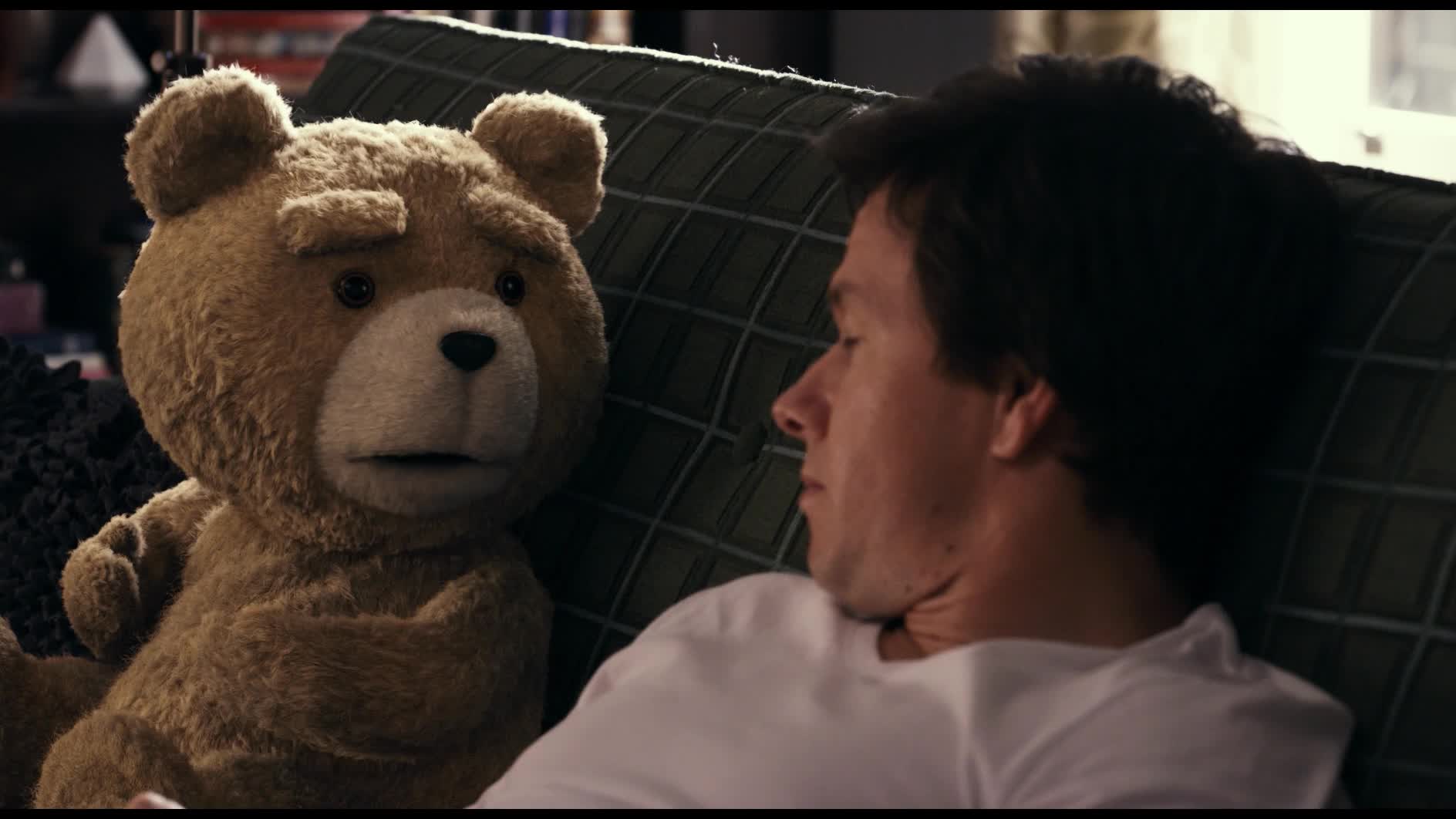 Still from Ted: the teddy bear sits beside his slumped human best friend on a couch