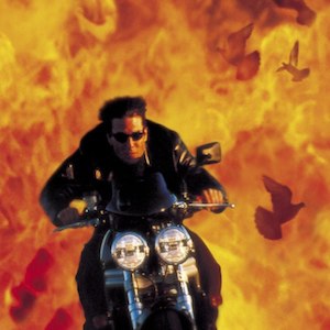 Still from Mission: Impossible II: Ethan Hunt rides a motorcycle out of a wall of fire as doves fly