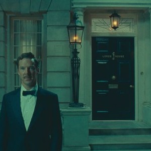 Still from The Wonderful Story of Henry Sugar: a man in a tuxedo stands outside a lamplit townhouse door