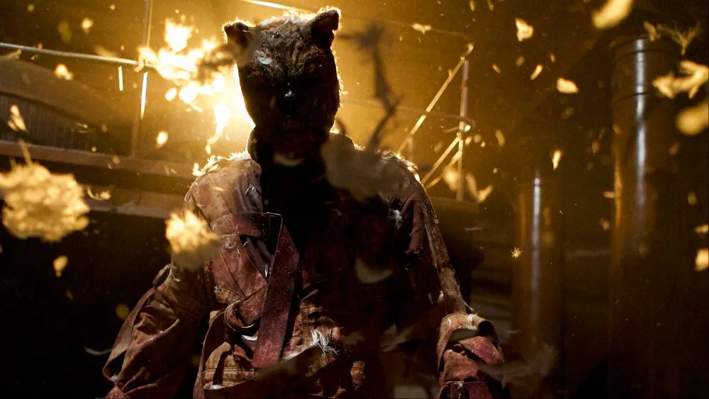 Still from Winnie-the-Pooh: Blood and Honey 2: the masked Tigger stands amid sparks and flying debris