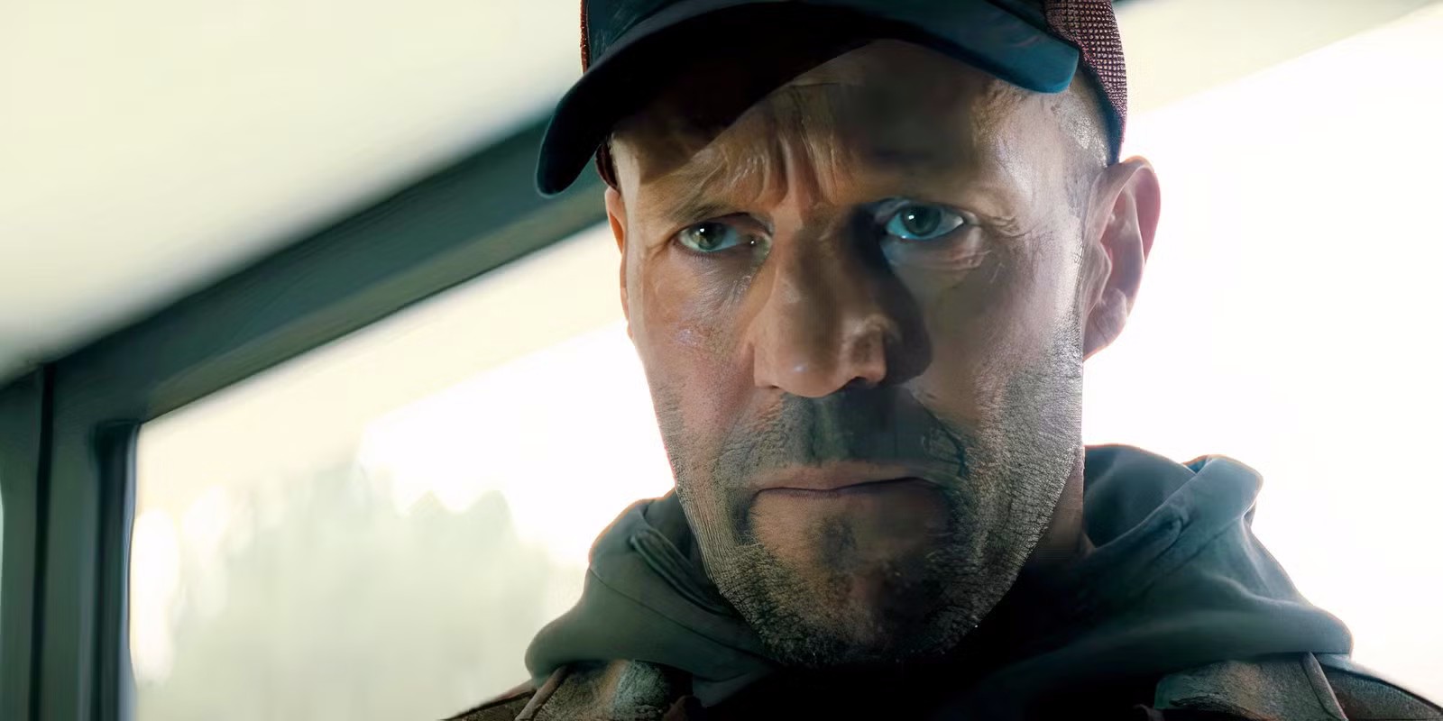 Still from A Working Man: Jason Statham in a cap and hoodie, staring intently