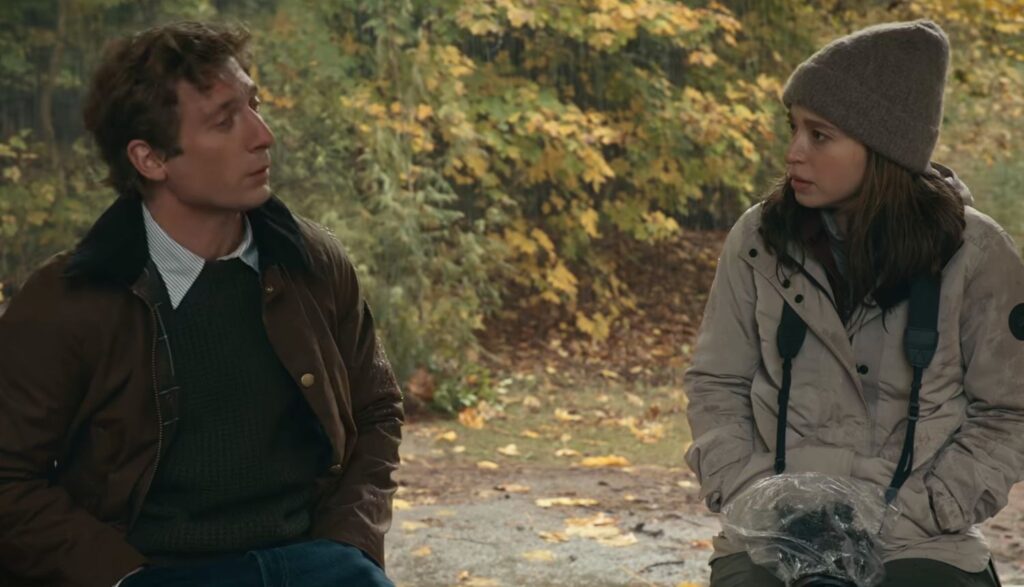 Still from The Social Reckoning: a man and a young woman in a knit hat talk on a bench among autumn trees